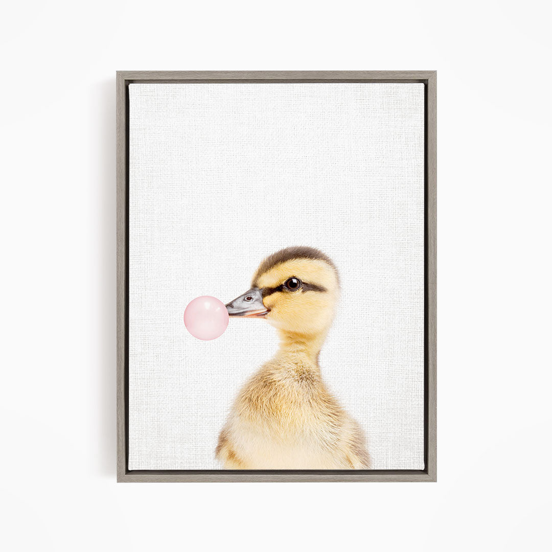 A cute duckling blowing a bubble with a pink bubble gum bubble.
