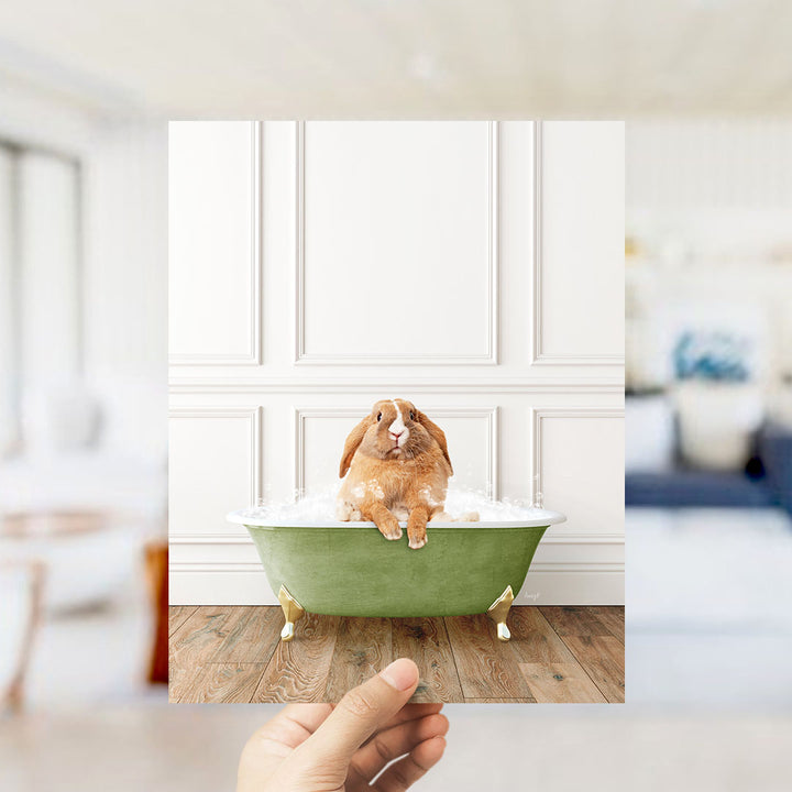 A brown rabbit sitting in a green bathtub filled with bubbles, with a blurred background suggesting a bathroom setting.