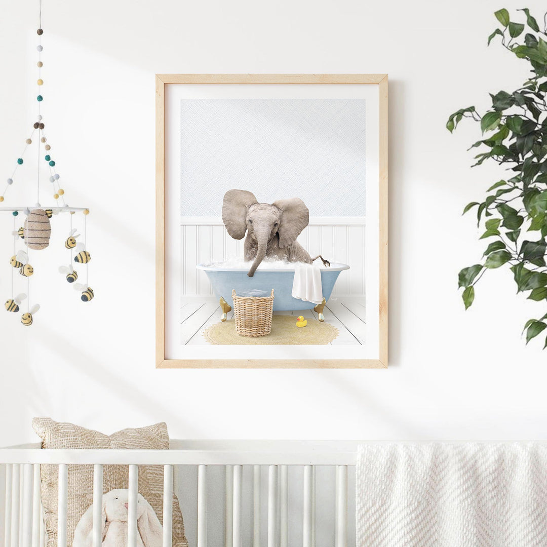 A framed image of an elephant sitting in a bathtub, surrounded by various decorative elements such as a hanging mobile, a plant, and a basket of toys.