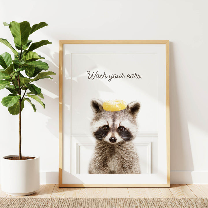 A framed poster with a raccoon wearing a yellow hat and the text "Wash your ears."