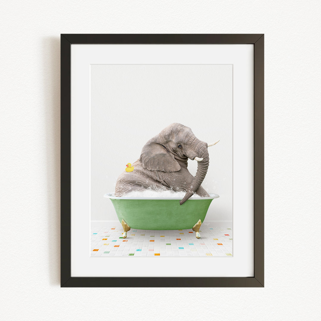 A gray elephant is sitting in a green bathtub filled with bubbles, with a yellow rubber duck floating nearby.