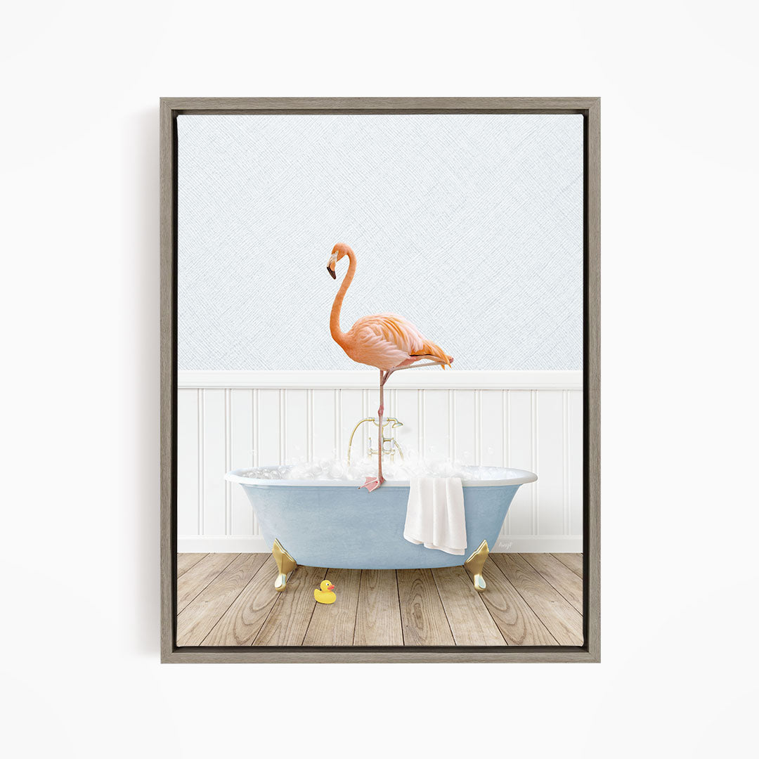 A pink flamingo stands on the edge of a blue bathtub filled with water, with a towel and rubber duckies nearby.
