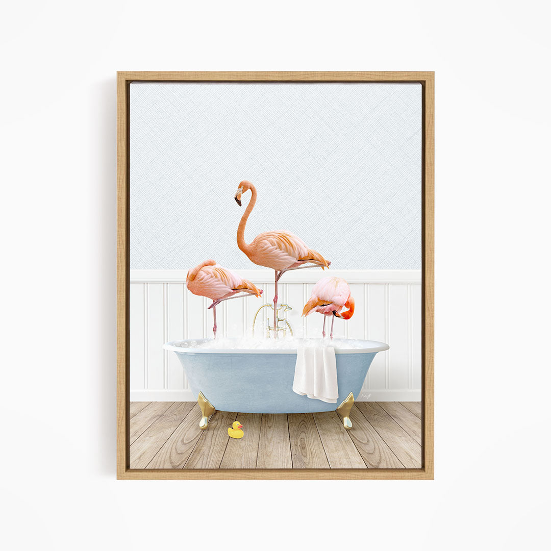 A framed image depicting three flamingos standing in a bathtub filled with water, with a towel hanging on the side.