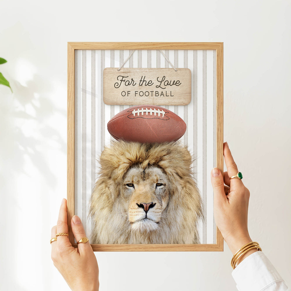A person's hands are holding a framed picture of a lion with a football on its head, displaying the text "Far the Love of Football".