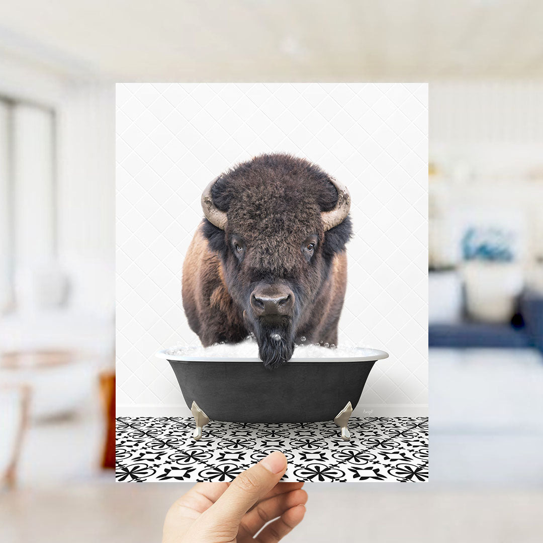 A close-up of a bison's head peeking out of a bathtub, with a hand holding the image up to the viewer.