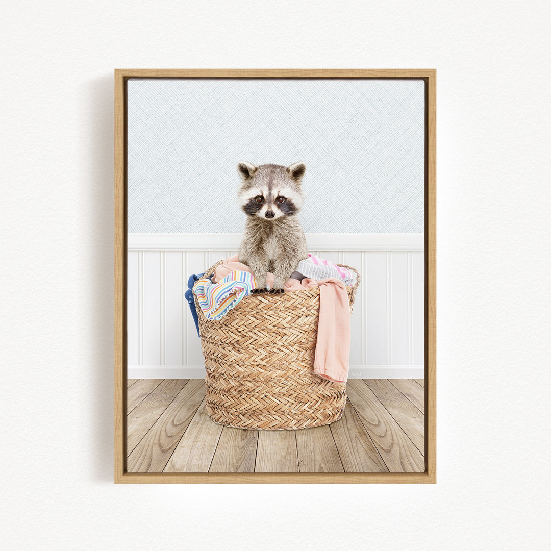 A raccoon sitting in a woven basket filled with clothes.
