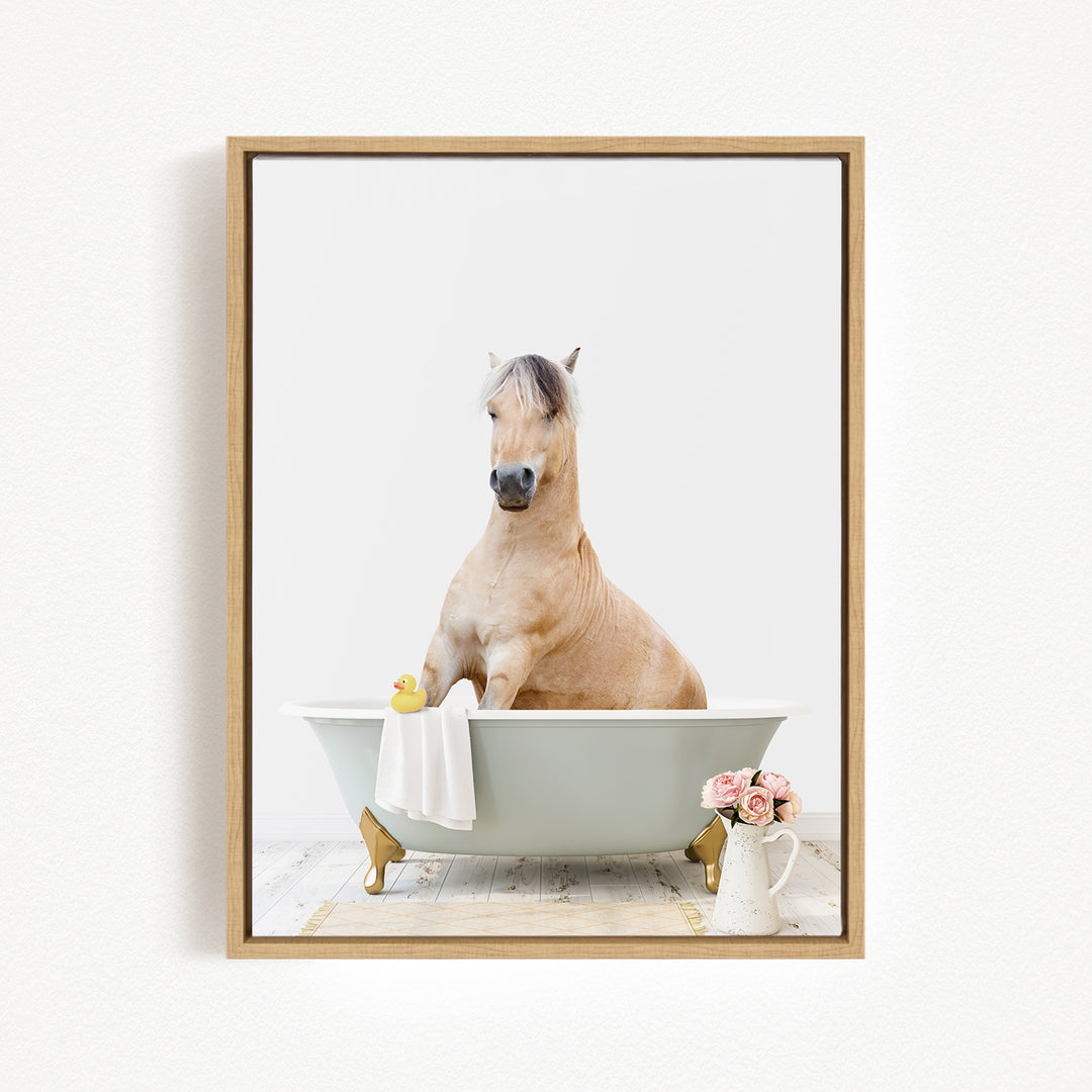 A light brown horse is sitting in a white bathtub, surrounded by a yellow rubber duck and pink flowers.