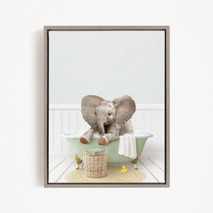 A gray elephant sitting in a green bathtub, surrounded by a basket of toys and a yellow rubber duck.