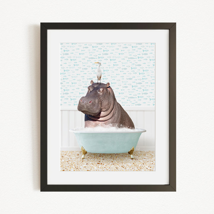 A framed image depicting a hippopotamus sitting in a bathtub, with a bird perched on its head.