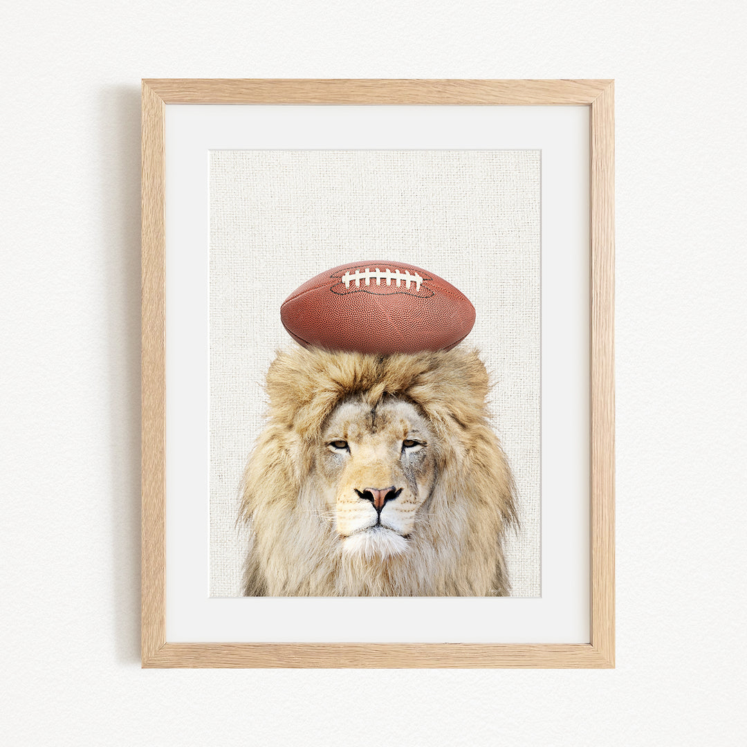 A framed image of a lion with a football on its head.