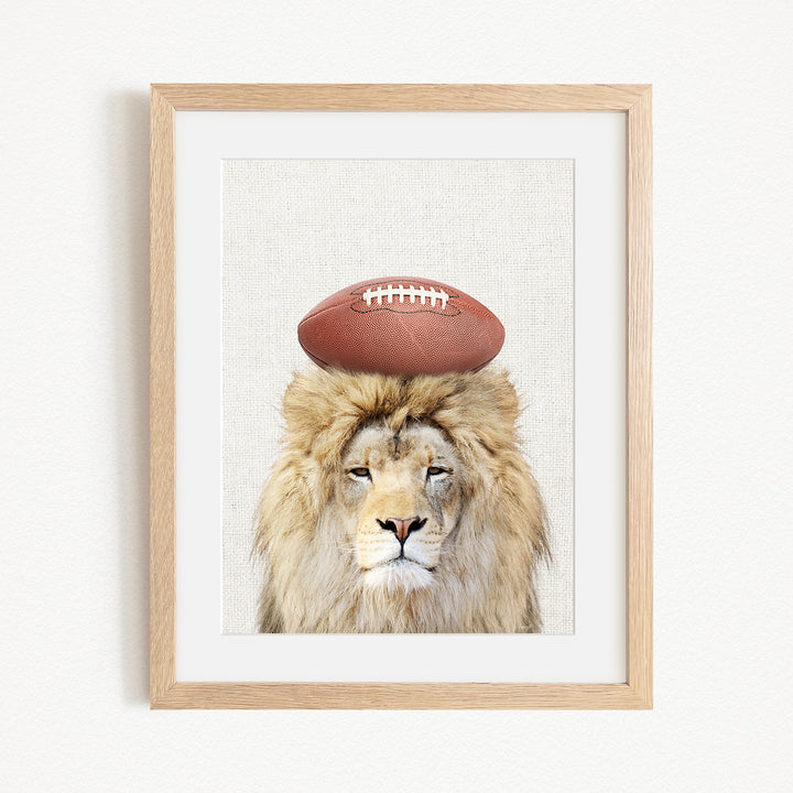 A framed image of a lion with a football on its head.