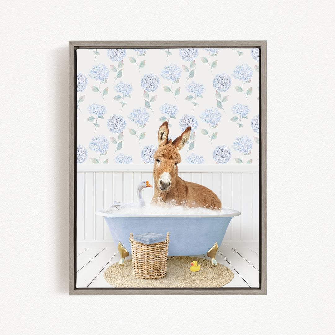 A donkey is sitting in a blue bathtub filled with bubbles, surrounded by a basket of toys and a yellow rubber duck.