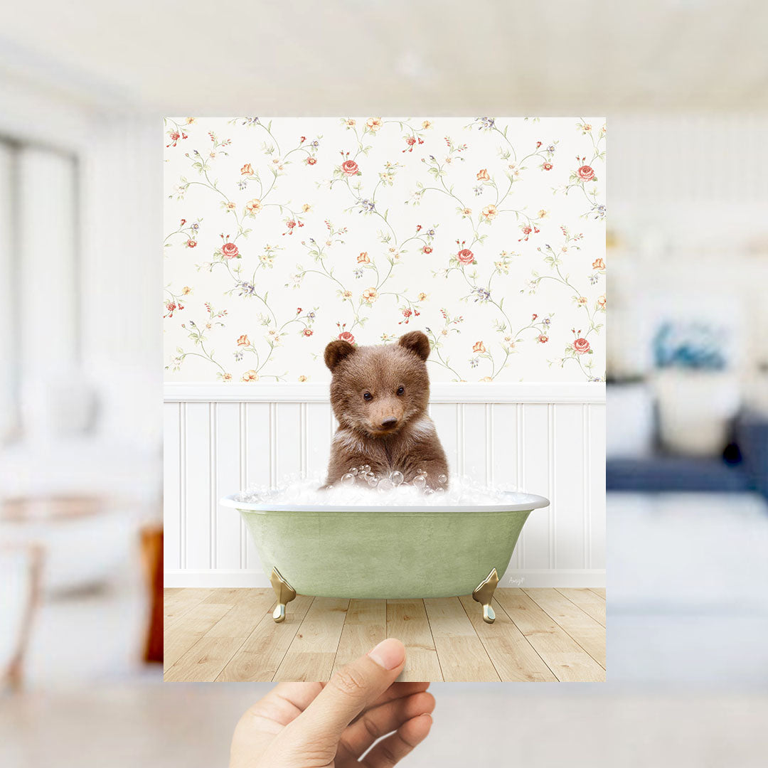 A brown bear sitting in a green bathtub filled with bubbles, with a floral wallpaper in the background.