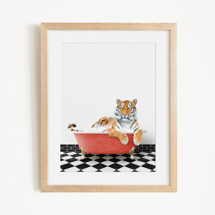 A tiger is sitting in a red bathtub on a black and white checkered floor.