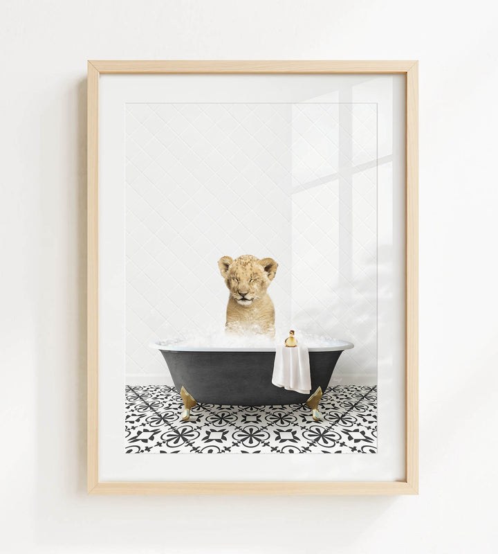 A young lion cub sitting in a bathtub filled with bubbles, surrounded by a black and white patterned floor.