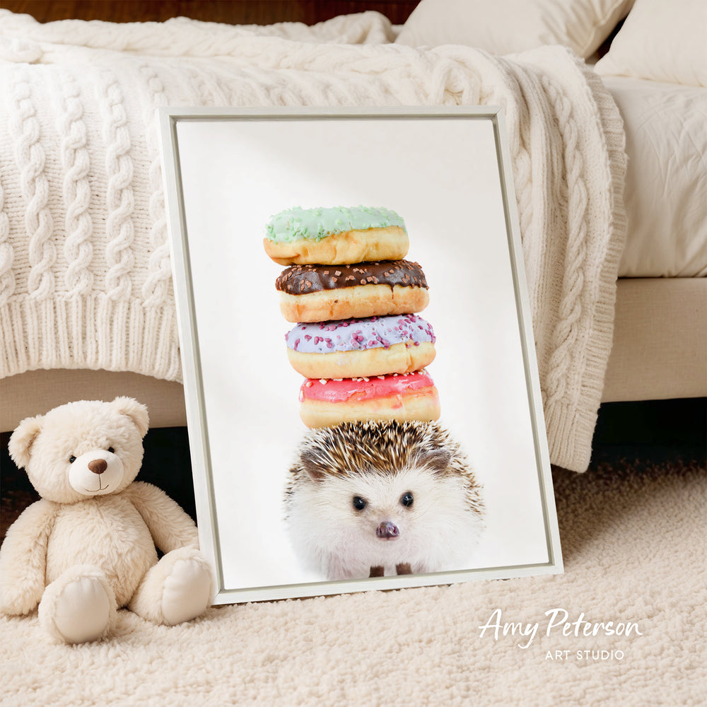 A framed image of a hedgehog sitting next to a stack of colorful donuts, with a teddy bear sitting next to the hedgehog.