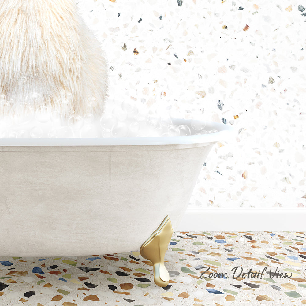 A fluffy white cat is sitting in a white bathtub filled with bubbles, with a mosaic floor in the background.