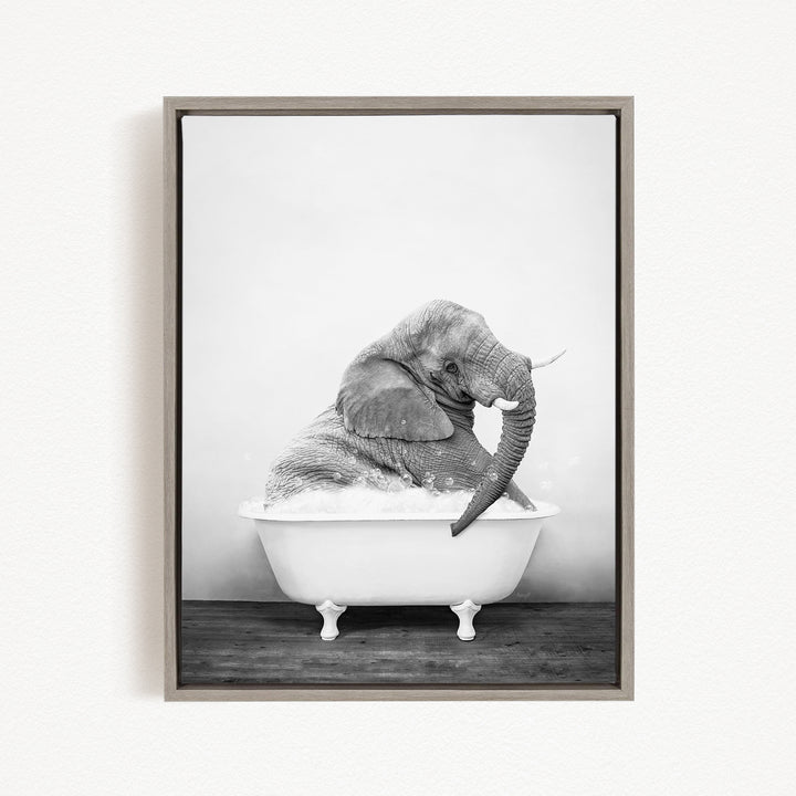 A black and white photograph of an elephant sitting in a bathtub filled with water.
