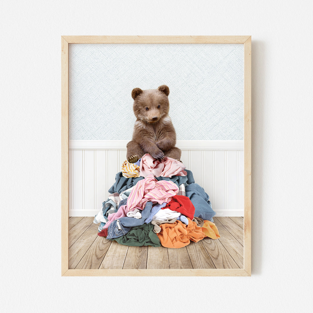 a brown teddy bear sitting on top of a pile of clothes