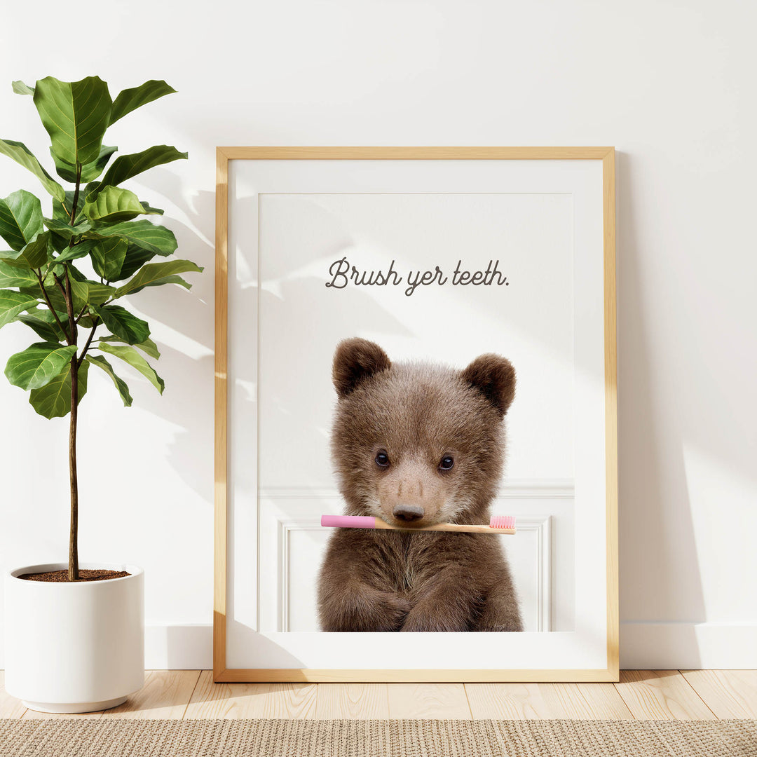 A framed image of a brown bear holding a pink toothbrush, with the text "Brush yer teeth" written above it.