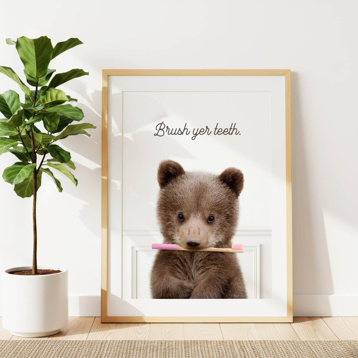 A framed image of a brown bear holding a pink toothbrush, with the text "Brush yer teeth" written above it.