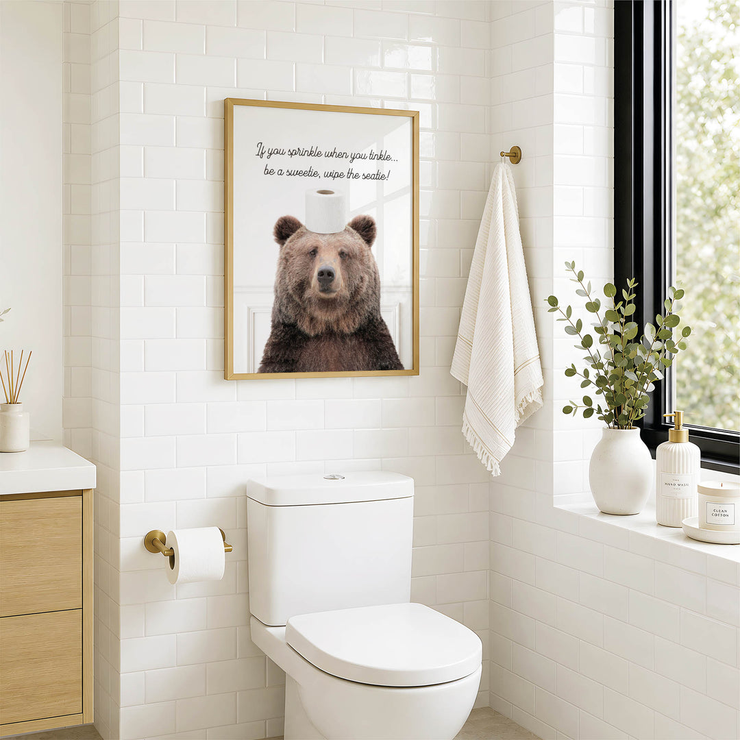 a bathroom with a toilet, a towel, and a framed picture of a bear on the wall.