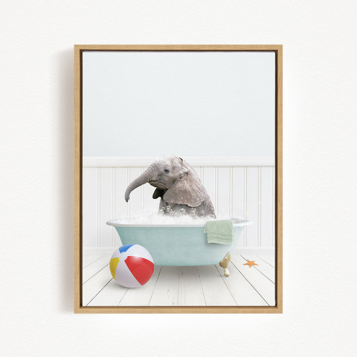 A baby elephant sitting in a bathtub filled with water, surrounded by a beach ball and a towel.