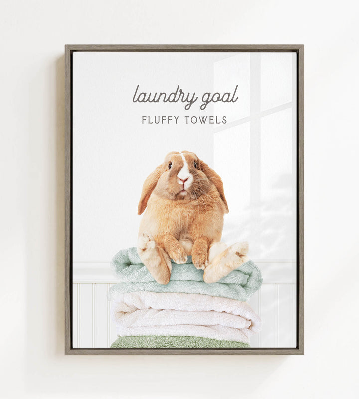 A fluffy rabbit sitting on a stack of towels, with the text "laundry goal" and "FLUFFY TOWELS" displayed above the image.