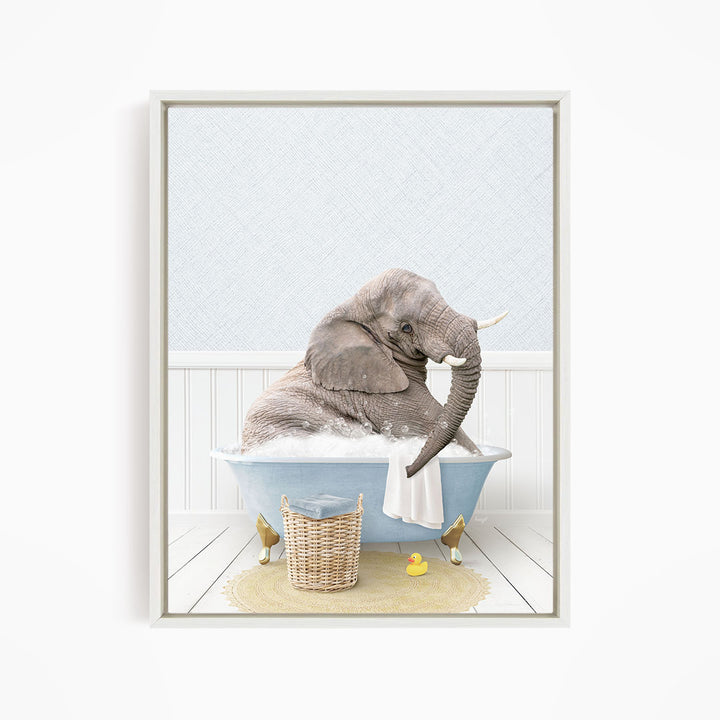 A gray elephant is sitting in a blue bathtub filled with water, surrounded by a yellow rubber duck and a wicker basket.