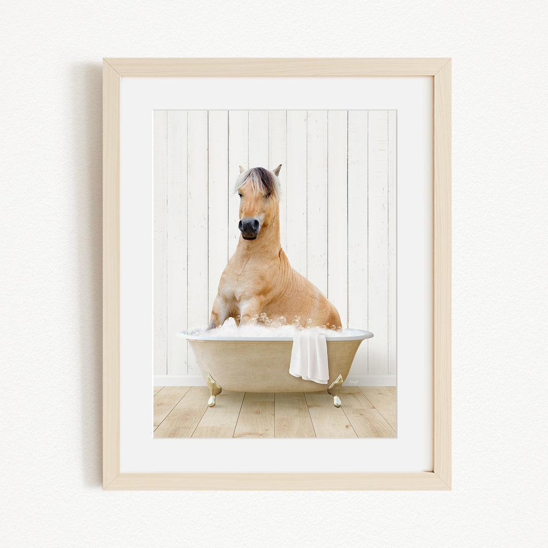 A light brown horse is sitting in a white bathtub filled with water, surrounded by a wooden floor and a white wall.