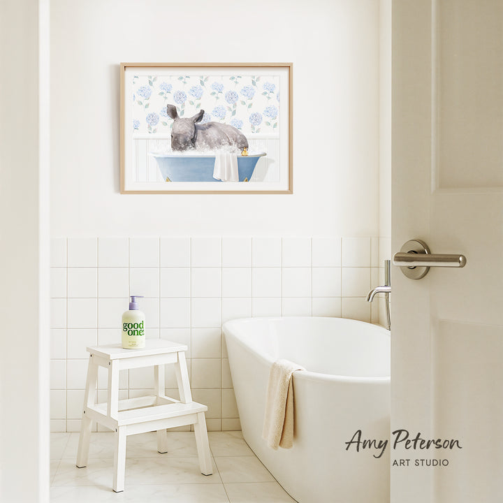 A bathroom interior with a white bathtub, a stool, and a framed painting of a rabbit in a bathtub on the wall.