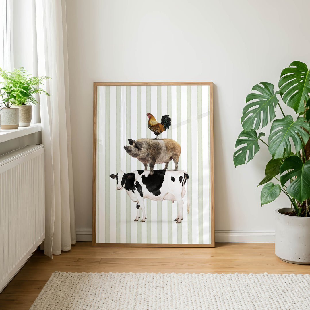 a framed picture of a cow, pig, and rooster standing on top of each other, with a window and potted plants in the background.