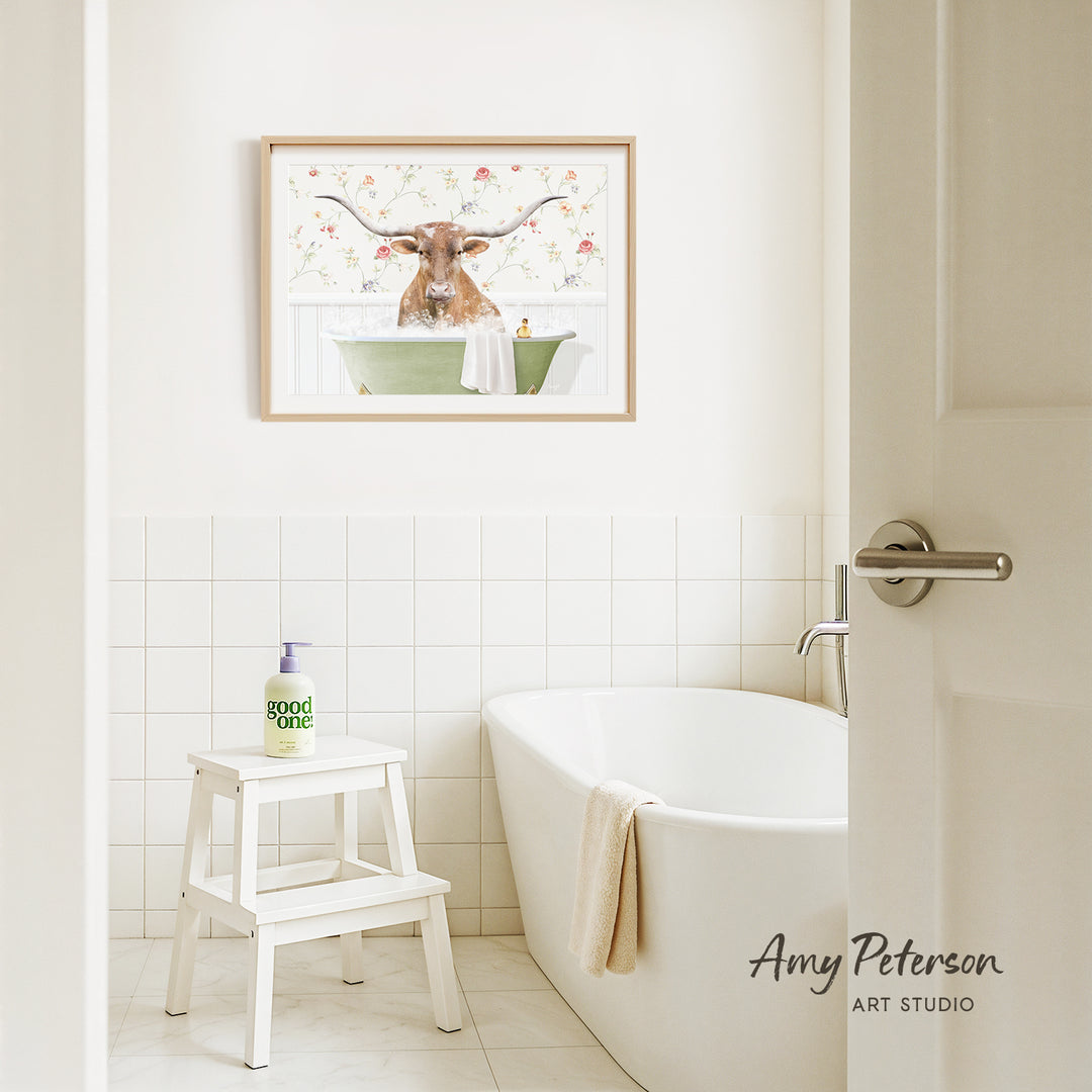 a bathroom with a framed picture of a bull with horns hanging on the wall above a white bathtub.