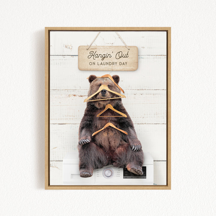 A framed image of a bear sitting on a washing machine, with a sign above it that says "Hangin' Out on laundry day".