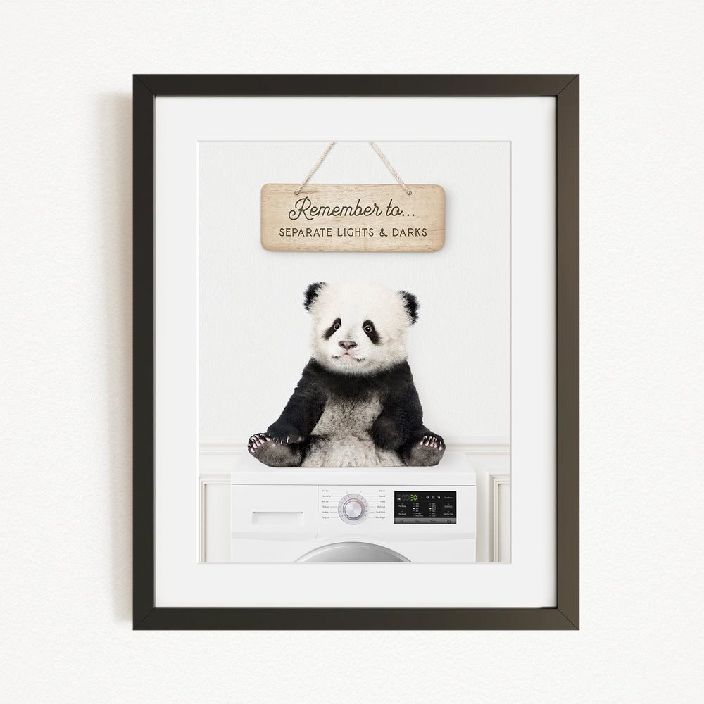 A panda bear sitting on a white washing machine with a wooden sign above it that says "Remember to separate lights & darks".