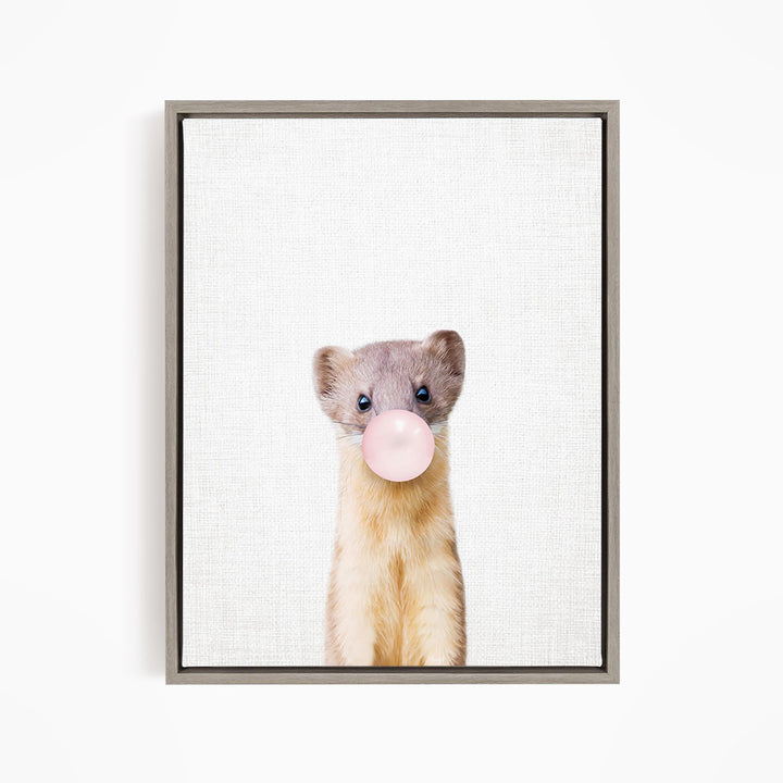 A cute beige and gray ferret is blowing a bubble with a pink bubble gum bubble.