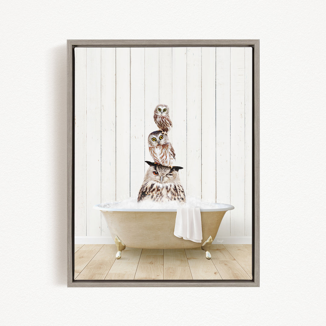 A framed image depicting three owls sitting in a bathtub, with one owl perched on top of the other two.