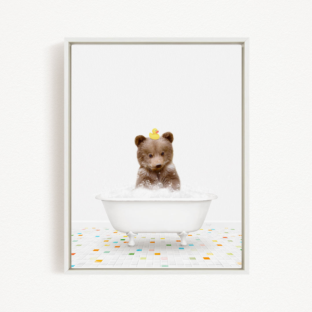 A brown bear sitting in a white bathtub filled with bubbles, with a yellow rubber duck on its head.