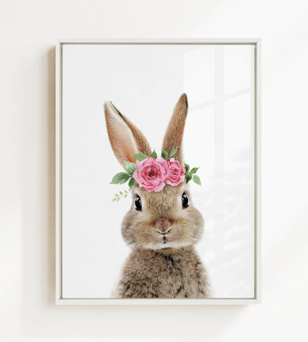 A cute bunny rabbit wearing a pink flower crown on its head, looking directly at the camera.