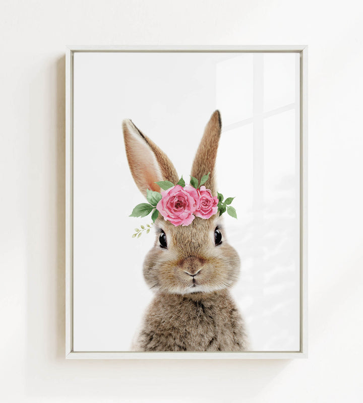 A cute bunny rabbit wearing a pink flower crown on its head, looking directly at the camera.