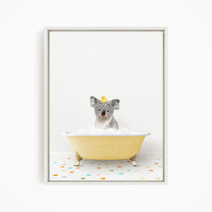 A gray koala bear sitting in a yellow bathtub filled with bubbles, wearing a yellow rubber duck hat.