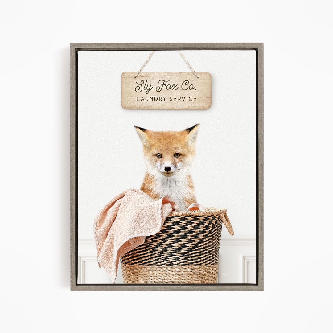 A framed image of a young fox sitting in a woven laundry basket, with a sign above it that reads "Laundry Service".