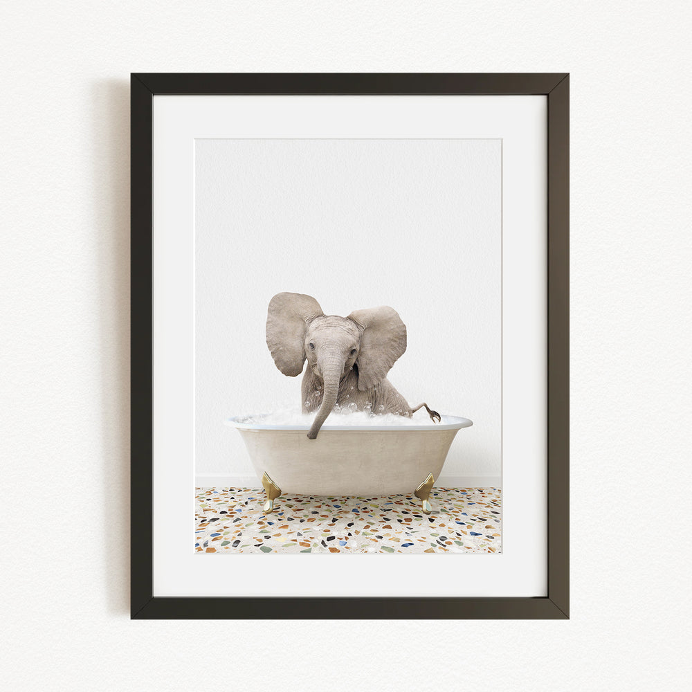 A baby elephant sitting in a bathtub filled with water, with its trunk submerged in the water.