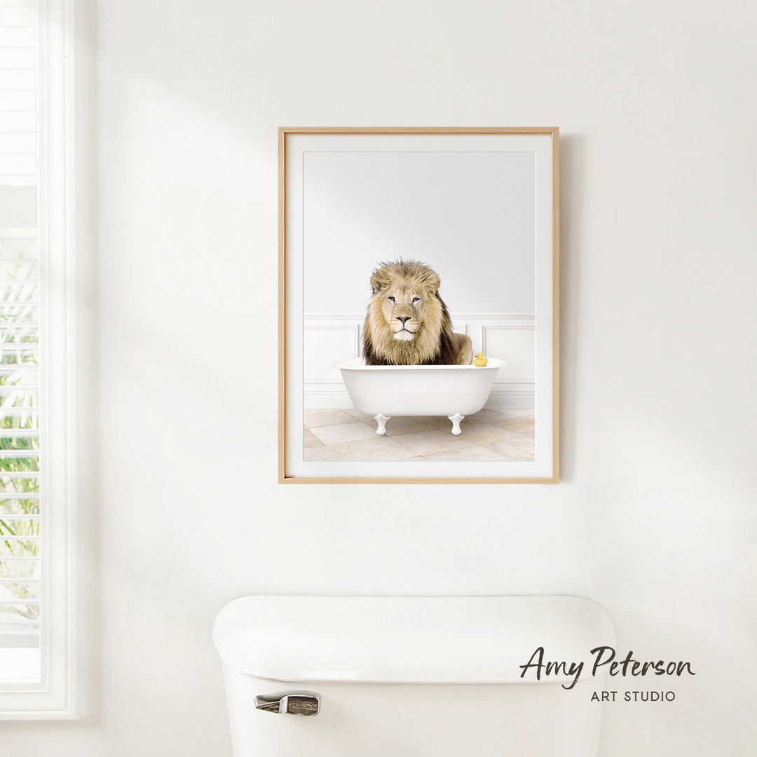 A framed image of a lion sitting in a white bathtub, with a yellow rubber duck floating in the water.