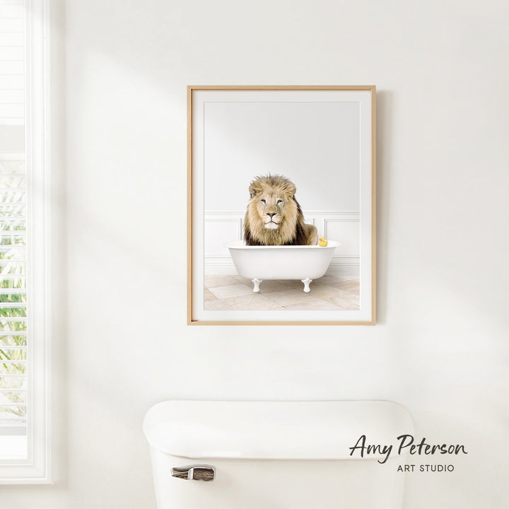 A framed image of a lion sitting in a white bathtub, with a yellow rubber duck floating in the water.