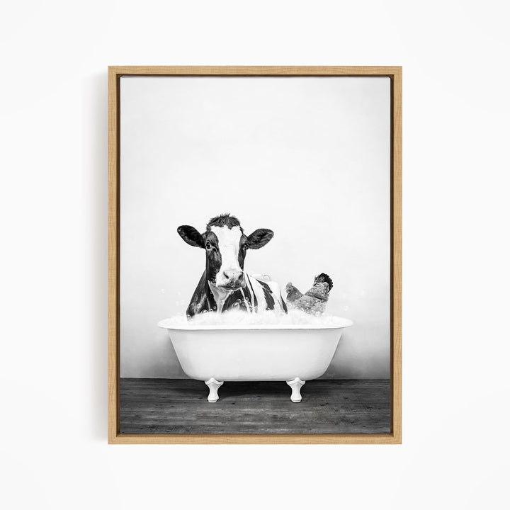 A black and white image of a cow sitting in a bathtub, with a chicken standing nearby.