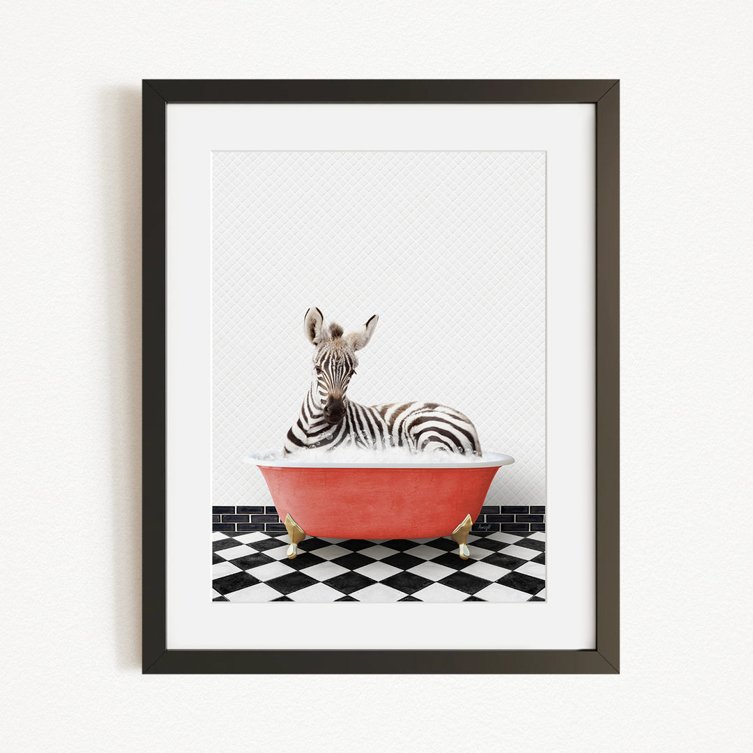 A zebra is sitting in a red bathtub on a black and white checkered floor.