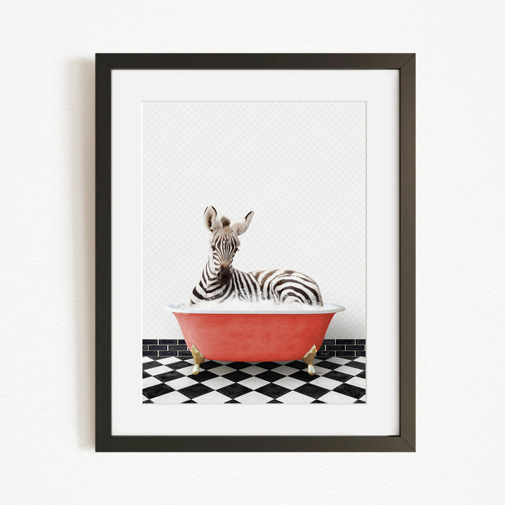 A zebra is sitting in a red bathtub on a black and white checkered floor.