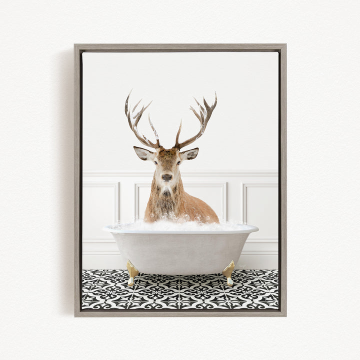 A deer with large antlers is sitting in a white bathtub filled with bubbles, creating a whimsical and unexpected scene.