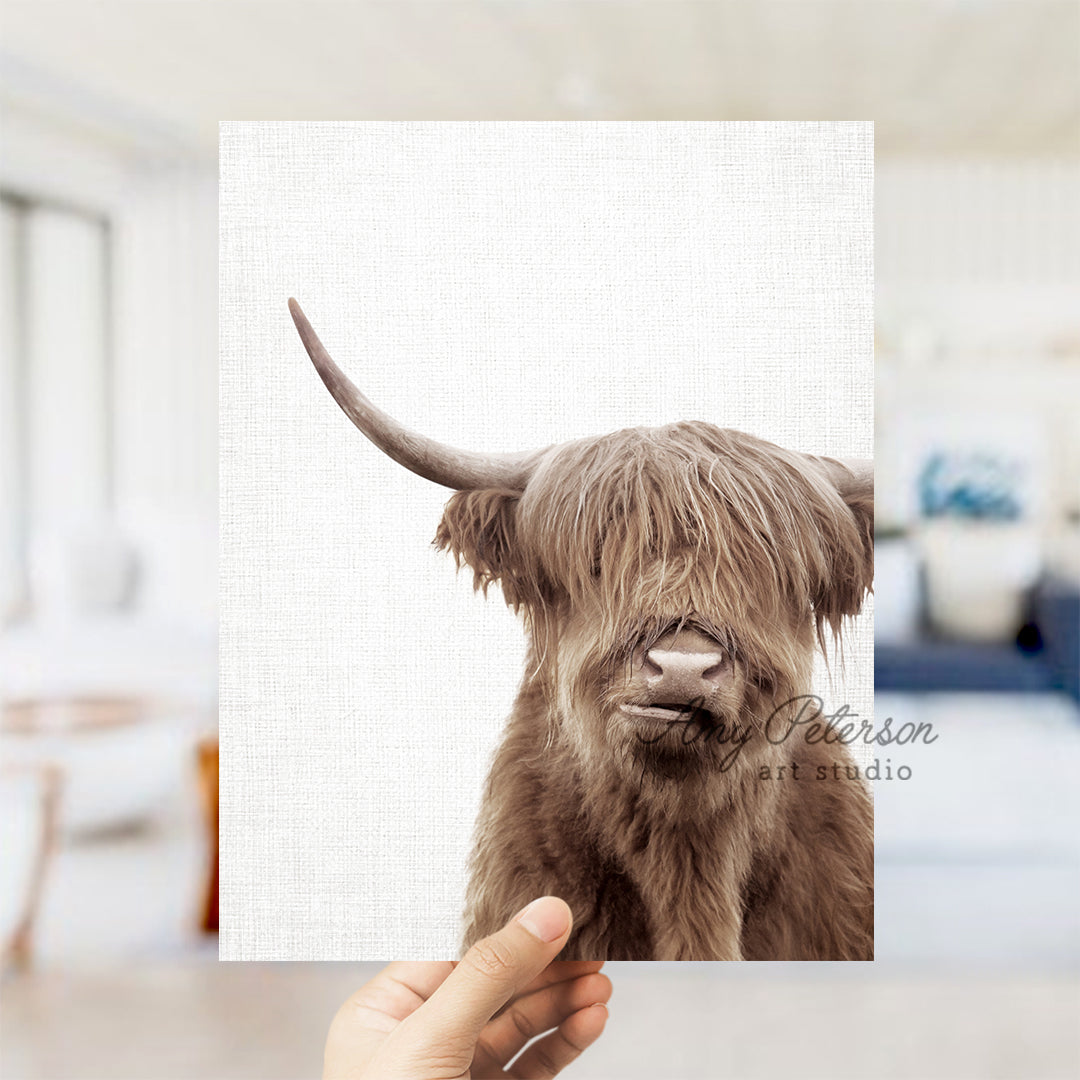 a hand holding up a picture of a brown cow